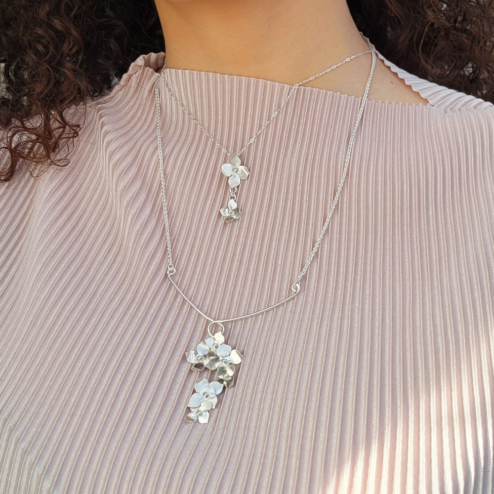 two necklaces on a light blush striped sweater on a model